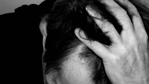 Psychische Belastung eine Person legt den Kopf in die Hände