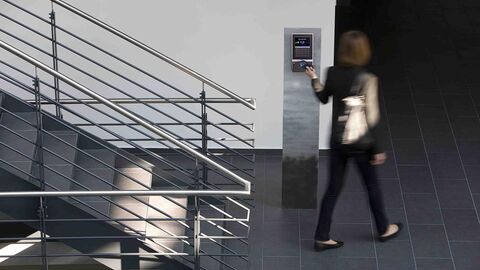 Arbeitszeit Person geht an einem Zeiterfassungsgerät vorbei und stempelt sich zum Dienstantritt ein.